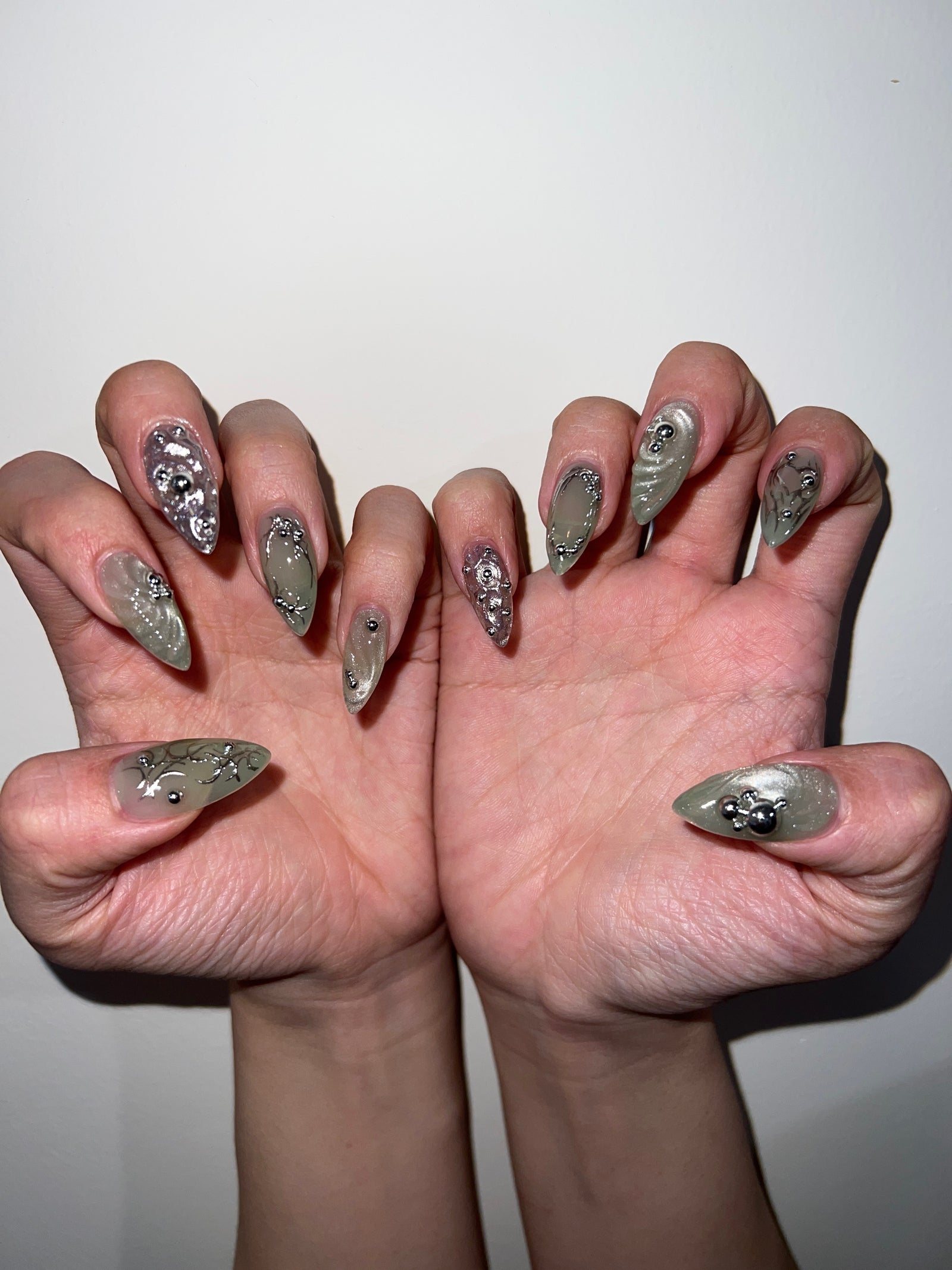 Olive chrome stiletto nails with silver stones and pearls