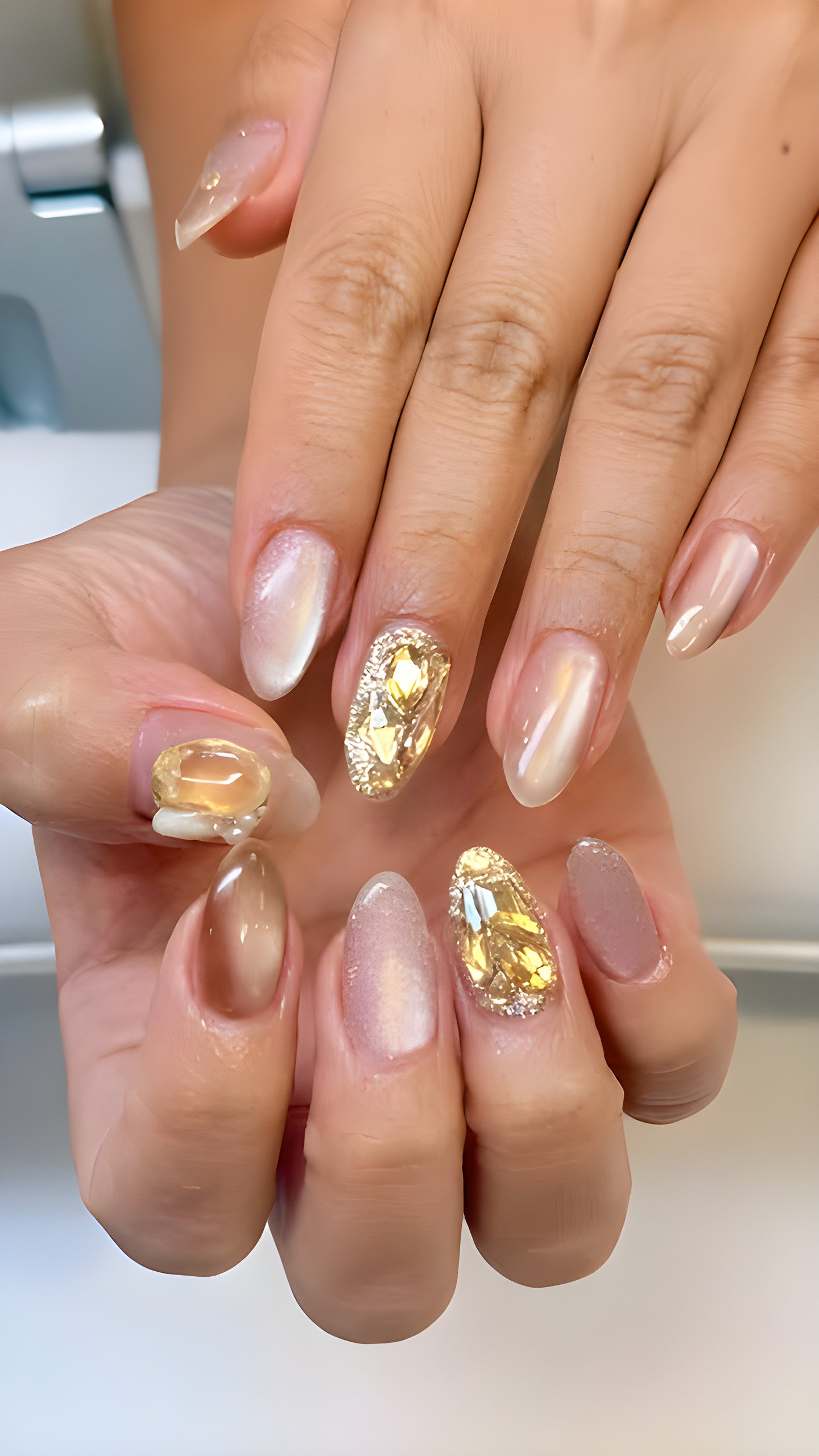 Nude chrome nails with large gold and crystal stones